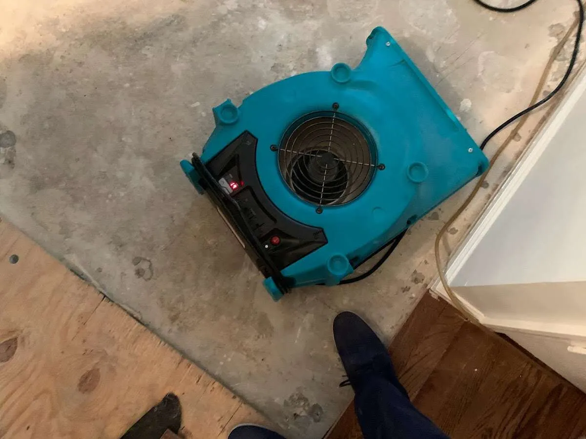 Air mover drying subfloor during Leak Detection & Repair in North Liberty